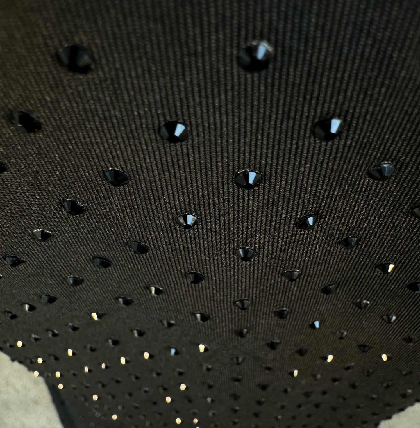 Looking down at Jet Black Crystals on Black Fabric Dotted T-shirt showing a close up of the rhinestone grid pattern and the sparkles as your focus shifts.