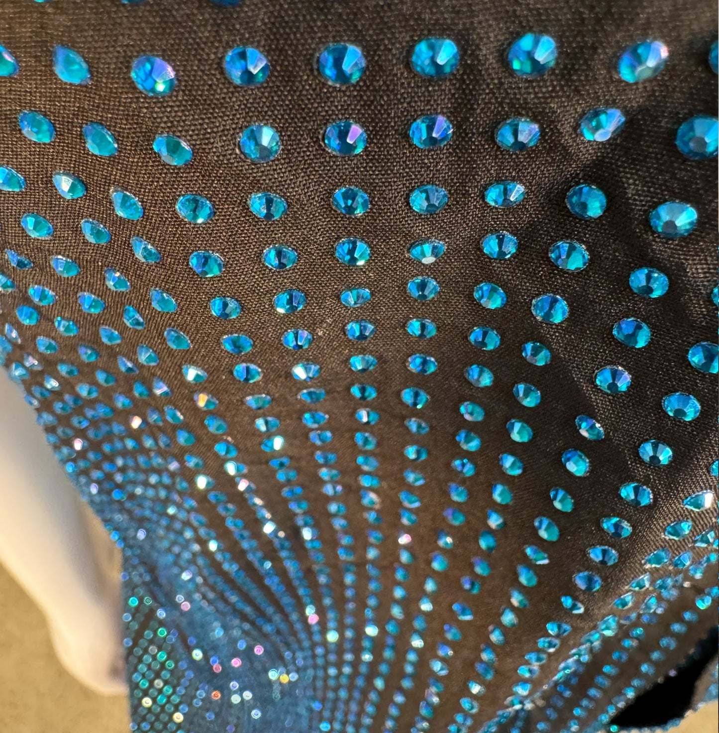 Looking down at Capri Blue Crystals on Black Fabric Dress Shirt (Short Sleeves) showing a close up of the rhinestone grid pattern and the sparkles as your focus shifts.